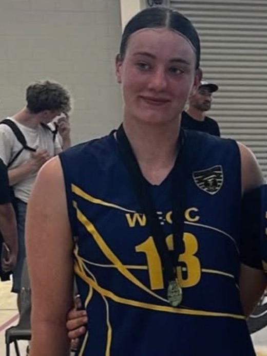 Zara Thomas courtside in a WEGC number 13 singlet, wearing a medal.